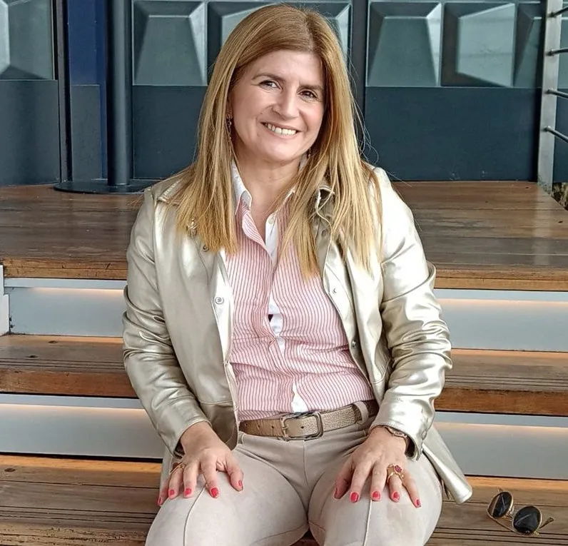 Pilar Díaz sentada en una escalera de madera, sonriendo